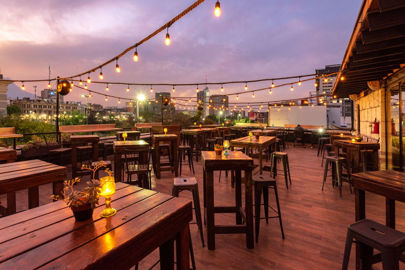 Mesas altas de la terraza con velas encendidas mientras cae la tarde
